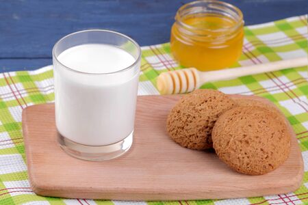 Oatmeal cookies with milk and honey on a board on a blue wooden tableの写真素材