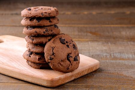 Tasty cookies with chocolate on the board on a brown wooden tableの写真素材