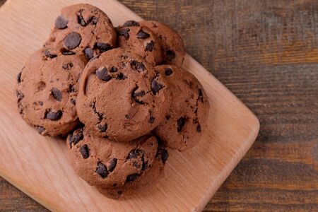 Tasty cookies with chocolate on the board on a brown wooden table. view from aboveの写真素材