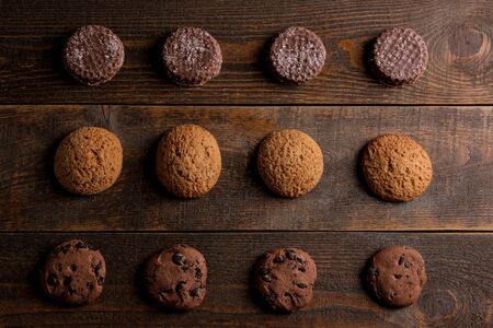 Different tasty cookies piled in a row on a brown wooden table. view from aboveの写真素材