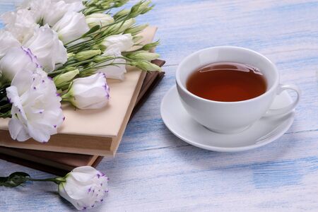 Beautiful white flowers. Eustoma bouquet with a stack of books on a blue wooden table.の写真素材