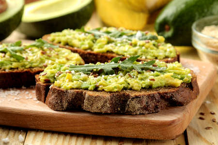 Avocado and arugula sandwiches closeup on natural wooden table. Sandwich with avocado puree.の写真素材