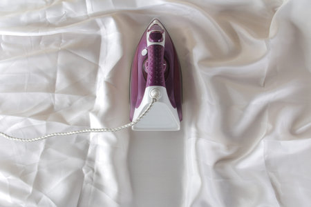 Lilac iron on a piece of white crumpled fabric. ironing clothes. household electrical appliances....