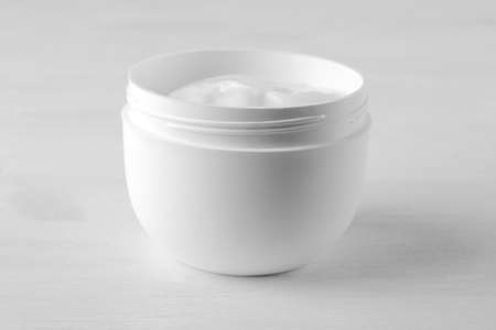 Face cream in a white jar on a white wooden backgroundの写真素材