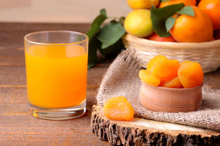 Dried apricots, apricot juice and fresh apricots on a brown wooden backgroundの写真素材