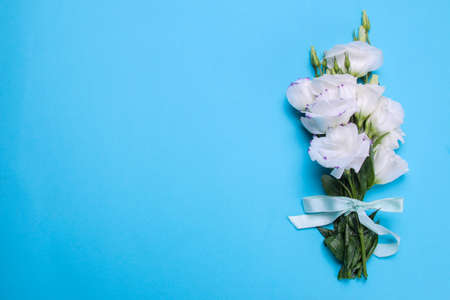 Beautiful white bouquet of flowers eustoma on a bright blue background top view with a place for an inscriptionの写真素材