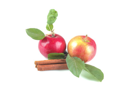 Ripe red apple with green leaves and cinnamon sticks on white isolated background