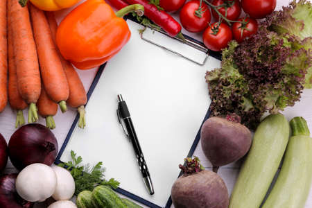 Fresh vegetables including lettuce leaves onion pepper beetroot carrots zucchini and tomatoes with a blank for recipes or for writingの写真素材