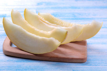Slices Fresh ripe melon on a wooden board on a blue wooden tableの写真素材