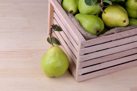A lot of fresh ripe pears in a wooden box on a natural wooden backgroundの写真素材