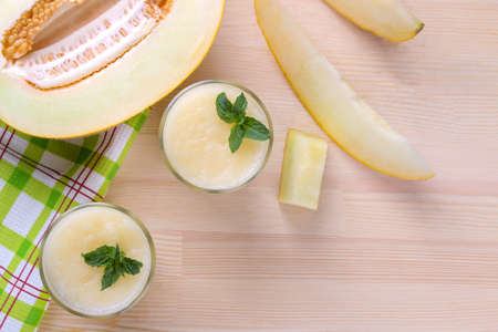 Smoothies of melon and fresh ripe melon on a natural wooden table. top viewの写真素材