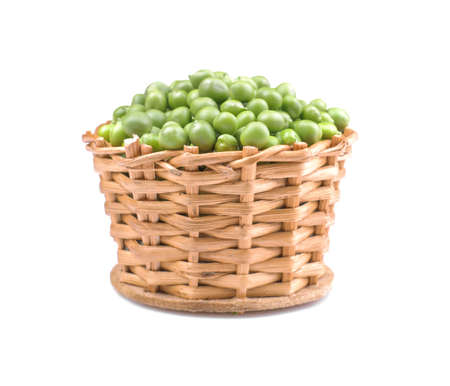 Green fresh peas in a wicker basket on a white isolated backgroundの写真素材