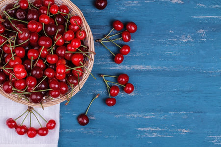 Composition with ripe cherries in a basket on a blue wooden table with a censer for the inscription....