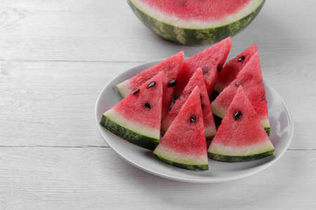 slices of fresh ripe watermelon on a cutting board on a white wooden tableの写真素材