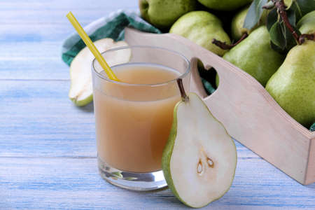 Pear juice in a glass with fresh ripe pears on a blue wooden tableの写真素材