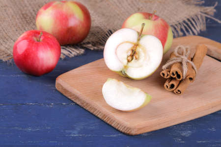 Fresh ripe red apples and cinnamon sticks on a blue wooden tableの写真素材
