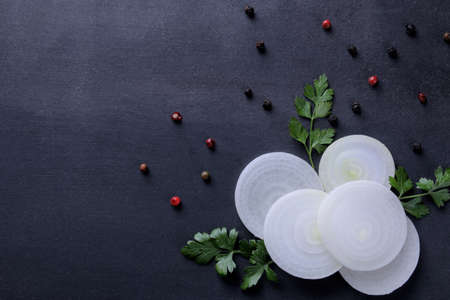 Rings cut into white onions with herbs and spices on a dark blue background. vegetables. top viewの写真素材