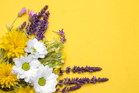 A bouquet of different wildflowers on a bright trendy yellow background with a place for the inscription. top viewの写真素材