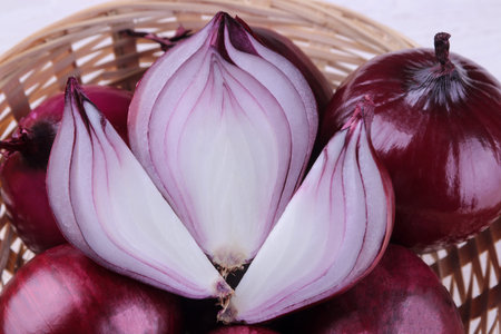 Fresh beautiful red onion in a close-up cut in a basket on a white wooden table