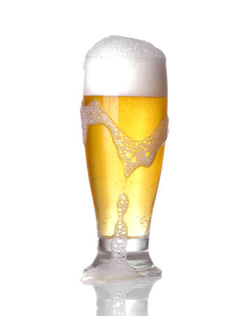 A glass of light beer in a glass with foam on a white isolated backgroundの写真素材