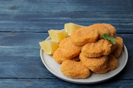 chicken nuggets on a plate with lemon slices on a blue wooden tableの写真素材