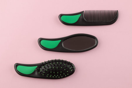 A set of different hair brushes and a mirror in one style on a bright pink background. view from...