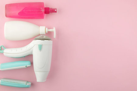 Various hair care products and hair accessories, curling iron and hair dryer, against a bright pink background. hair cosmetics. top view with place for text.の写真素材