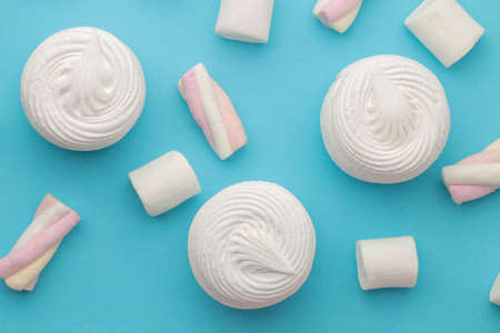 Background of sweet white marshmallows and small marshmallows on bright trendy blue background. Sweets. dessert. view from aboveの写真素材