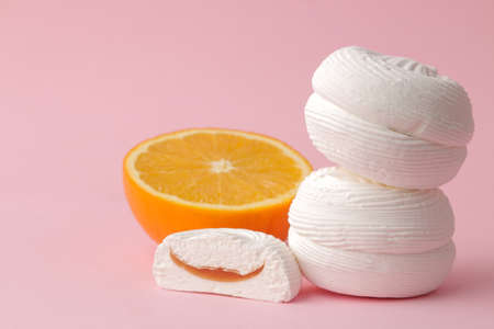 Sweet white round marshmallows with orange filling and oranges on a bright trendy pink background. Sweets. dessert.の写真素材