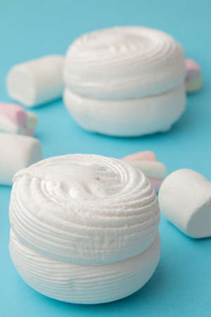 Background of sweet white marshmallows and small marshmallows on bright trendy blue background. Sweets. dessert.の写真素材