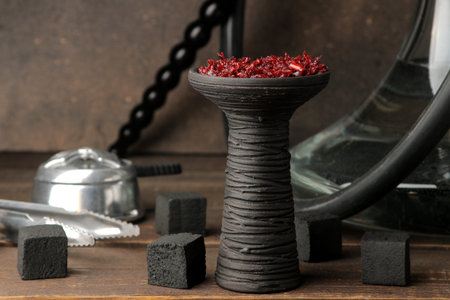 clay bowl for hookah with tobacco and various accessories for making hookah. coals, tongs, kolaud on...
