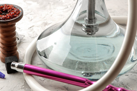 Transparent hookah with a beautiful pink mouthpiece and a clay bowl with tobacco and various...