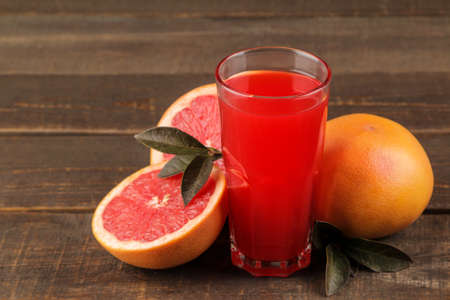 Citrus juices. grapefruit juice in a glass with fresh fruit on a brown wooden tableの写真素材