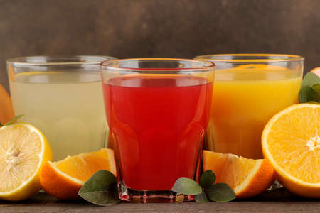 Citrus juices. Lemon, grapefruit and orange juice with fresh fruits on a brown wooden tableの写真素材