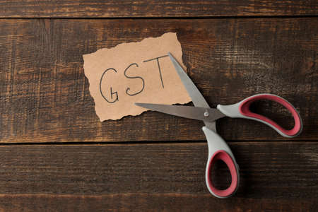 Word GST with scissors on a brown wooden background. view from aboveの写真素材