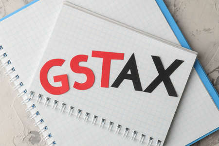The word GST TAX with a notepad on a light concrete background. view from above. close-upの写真素材