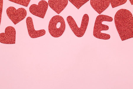 Bright red hearts and text love on a bright pink background. frame of hearts, top view with space...
