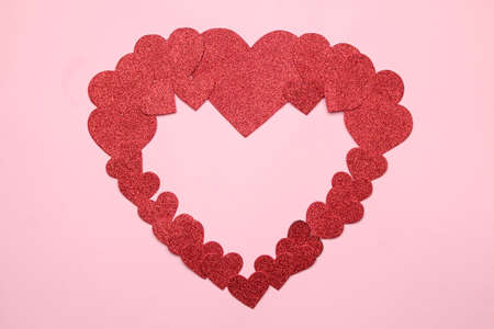 A big heart of small red hearts on a bright pink background. frame of hearts, top view with space for textの写真素材