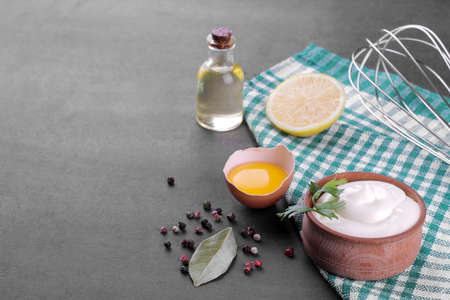 Mayonnaise in a wooden bowl and ingredients for making mayonnaise on a black background. white sauce. with space for textの写真素材