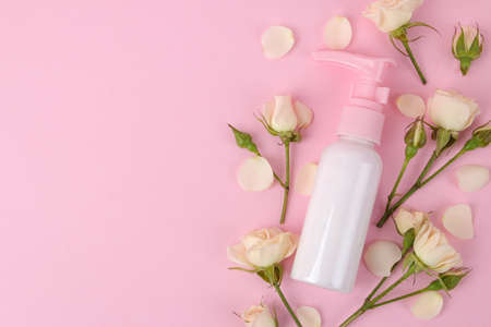 cosmetics for face and body in pink bottles with fresh roses on a delicate pink background. view from above. space for textの写真素材