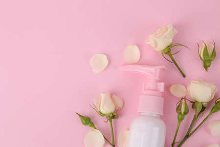 cosmetics for face and body in pink bottles with fresh roses on a delicate pink background. view from above. space for textの写真素材