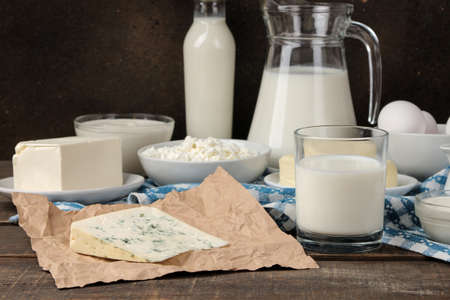 milk products. milk, sour cream, cheese, butter and cottage cheese on a brown wooden tableの写真素材