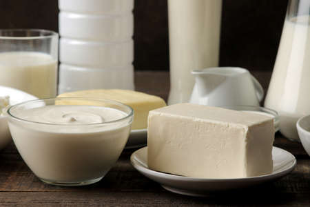 milk products. milk, sour cream, cheese, butter and cottage cheese on a brown wooden tableの写真素材