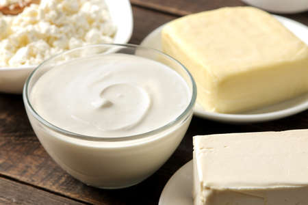 milk products. milk, sour cream, cheese, butter and cottage cheese on a brown wooden tableの写真素材