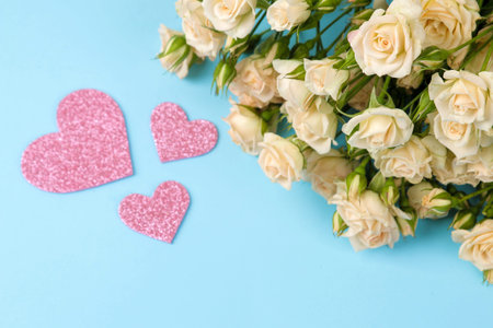 Beautiful mini roses with a pink heart on a bright blue background. holidays. Valentine's Day....