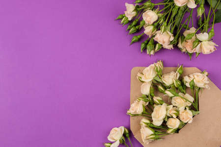 Beautiful mini roses in envelope with notepad on a bright lilac background. holidays. Valentine's Day. women's day. top view. space for textの写真素材