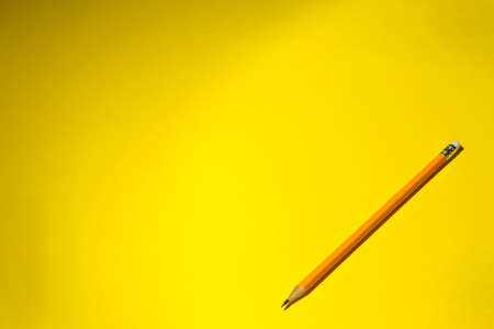 one yellow pencil on a bright yellow background with a hard shadow. stationery. space for textの写真素材