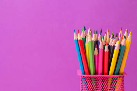 many colored pencils in a pink glass on a bright trendy lilac background. space for textの写真素材