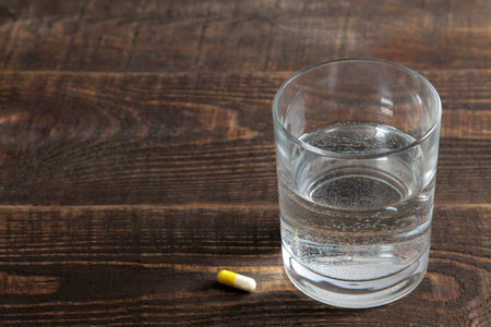 Depression concept. a glass with water and a tablet on a wooden brown table. place for text.