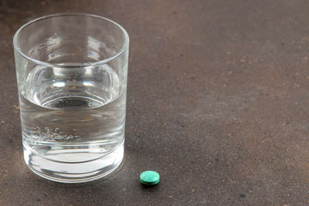 Depression concept. Psychological illness. a glass with water and a tablet on a dark background. place for text.の写真素材